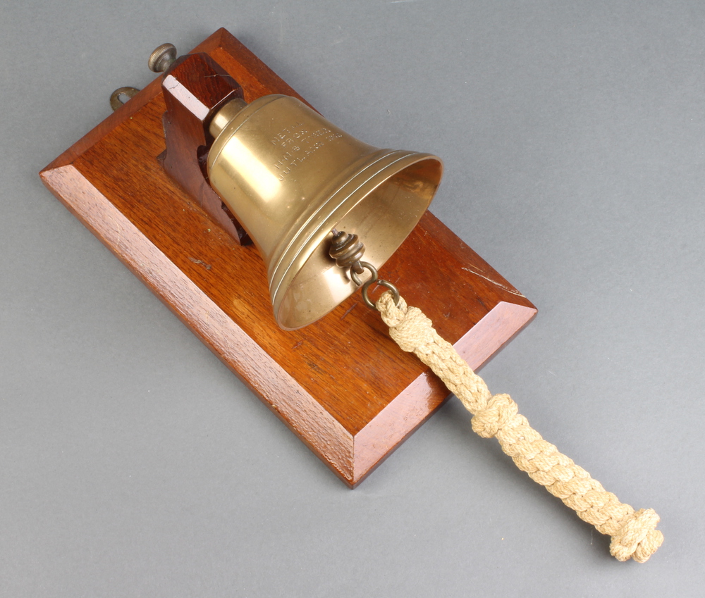A brass wall mounted bell raised on a mahogany stand, 26th February